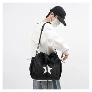 Detail of black crossbody bag with white star logo worn by model in street style fashion