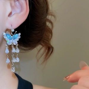 Macro shot of silver butterfly tassel earrings with blue zircon and water drop accents