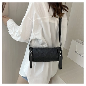 Detail of black cylindrical crossbody bag featuring unique pleated embossed texture
