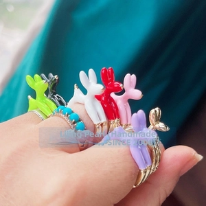 Detail of colorful enamel balloon dog rings with micro-inlaid accents on model's hand