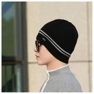 Close-up of black knit beanie with gray stripes and small logo patch on male model