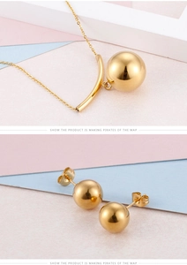Macro detail of high-polished gold spherical pendant necklace and matching stud earrings