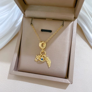 Detailed view of gold necklace with leaf, evil eye and Hamsa charms in a jewelry box