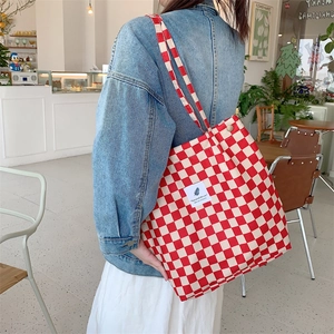 Close-up of red and white checkered corduroy tote bag worn on a woman's shoulder