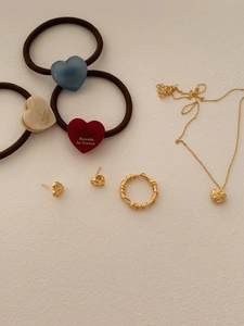 Detailed set of gold heart jewelry with red blue and beige resin accessories on white paper