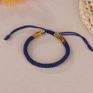 Detail of navy blue hand-woven braided rope bracelet with colorful knots and adjustable cord