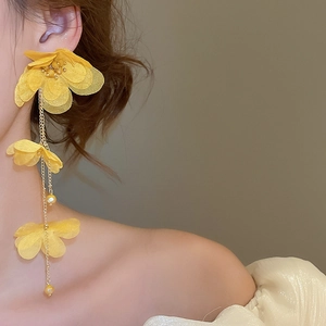 Detail of yellow fabric flower tassel earrings with pearls on a female model
