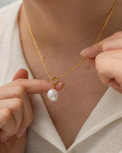 Elegant gold titanium necklace featuring a natural white pearl pendant on a model