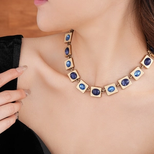 Nahaufnahme einer Vintage-Goldkette mit quadratischen blauen Edelsteinen im Retro-Stil
