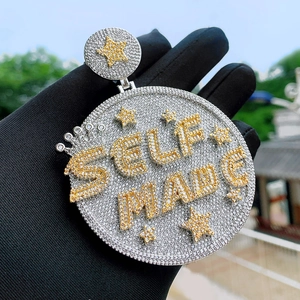 Macro shot of gold and silver hip hop pendant with SELF MADE cubic zirconia lettering