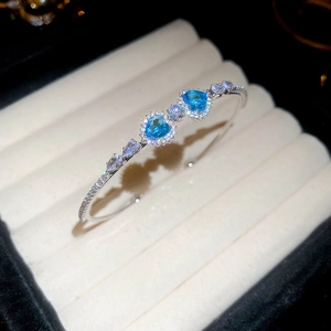 Close-up of heart-shaped sea blue gems and zircons on a silver open bangle