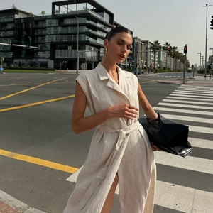 Detail of sleeveless mid-length dress featuring classic lapel and waist tie in beige