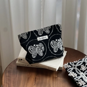 Linen canvas cosmetic bag in black with white butterfly embroidery and woven label