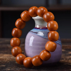 Polished Taihang Thuja wood prayer beads on a ceramic vase with a dark red finish