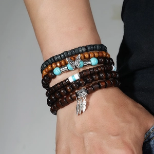 Close-up of multilayer beaded bracelet with silver butterfly and feather charms