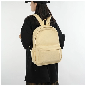 Detail of beige corduroy backpack on model showing strap texture and side pockets