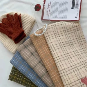 Flat lay of plaid scarves with heart embroidery, knit gloves, and a beanie hat set