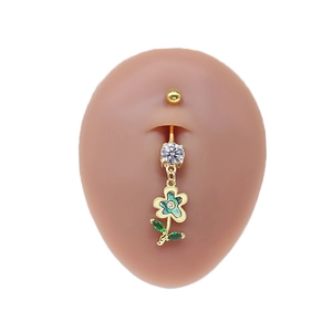 Detail of golden flower navel ring with white zircon and green leaves on skin model