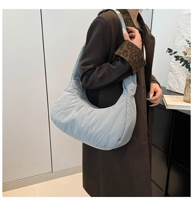 Quilted cloud shoulder bag in light blue nylon fabric worn by model in minimalist interior