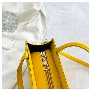 Détail supérieur du sac à main en PU jaune avec fermeture éclair dorée et double anse
