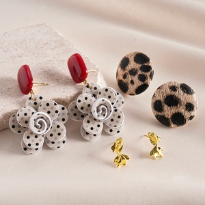 Detail of vintage earring set featuring leopard print studs and beige floral pendants