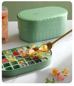 Detail of mint green ice cube tray showing fresh fruit cubes and storage box