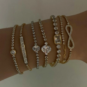 Stack of six gold and silver zircon tennis bracelets with infinity and geometric charms