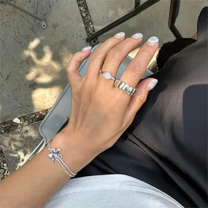 Close-up of S925 sterling silver oval ring and flower pendant bracelet on hand
