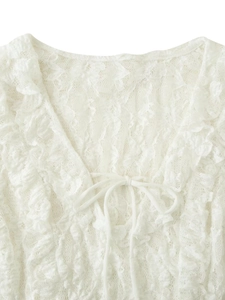 Close-up of white lace V-neck top featuring delicate bow tie and ruffle trim details
