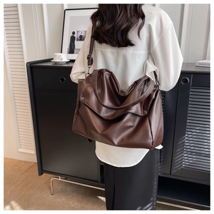 Detail of dark brown lychee leather tote bag with slouchy design and metal rivets
