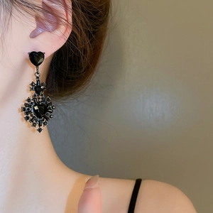 Close-up of black heart earring with sparkling cross inlay on model's ear