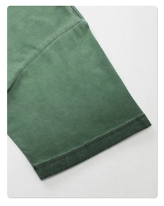 Detailed close-up of double-stitched hem on vintage washed green cotton t-shirt