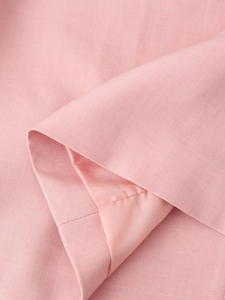 Detailed macro view of pink blazer fabric showing smooth lining and premium stitching