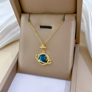 Dettaglio della collana pianeta oro con gemma blu e cristalli sulla seta