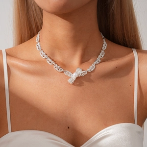Detail of silver lace necklace with bow pendant and faux pearl on model's neck
