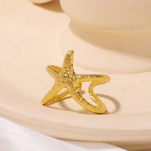 Starfish shaped gold ring with textured hammer finish on a ceramic display