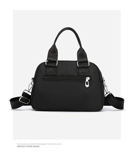 Close-up of black nylon handbag featuring front zipper pocket and adjustable shoulder strap