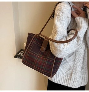 Detail of vintage plaid woolen tote bag with brown leather strap and buckle closure