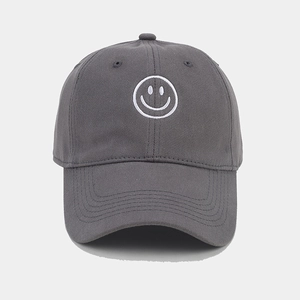 Detailed close-up of white smiley face embroidery on a charcoal grey cotton baseball cap