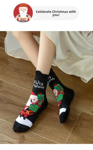 Detail of black Christmas socks with Santa Claus patterns and fuzzy pompoms on wood floor