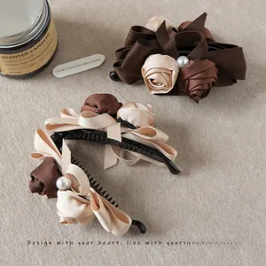 Detail of rose ribbon banana clip with pearl center on aesthetic beige fabric