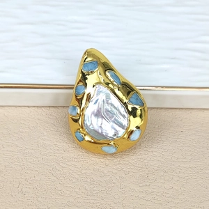 Detailed view of teardrop baroque pearl pendant with gold plating and blue gemstones