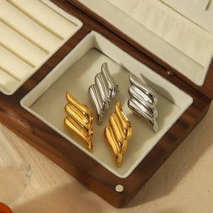 Polished 18k gold and silver wing-shaped textured earrings set in a wooden jewelry box