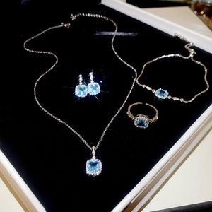 Macro shot of sea blue square gemstone jewelry set in a black velvet display box