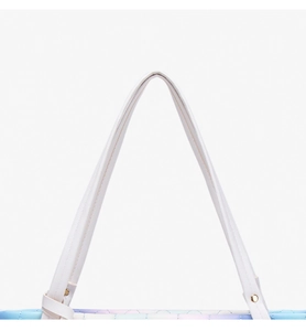 Close-up of white leather handles and gold studs on a gradient quilted tote bag