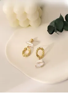 Detailed view of asymmetric gold lava texture earrings with baroque pearls on a tray