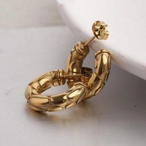 Macro detail of 18K gold-plated C-shaped hoop earrings with textured snake-link pattern
