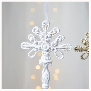 Macro shot of white resin Christmas wing ornament with glitter finish and warm bokeh lights