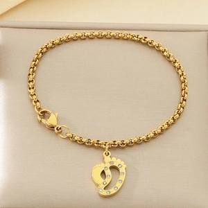 Vue macro du pendentif empreintes doré avec cristaux sur chaîne à perles acier
