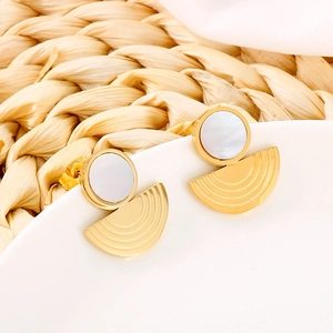Elegant gold-tone geometric hoop earrings with white shell inlay on a ceramic display